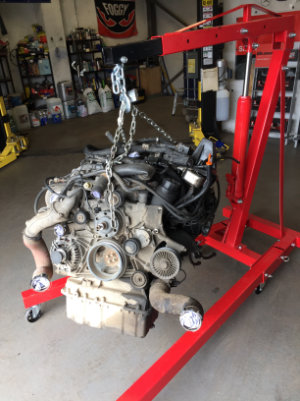 An engine being hoisted by a red engine hoist.